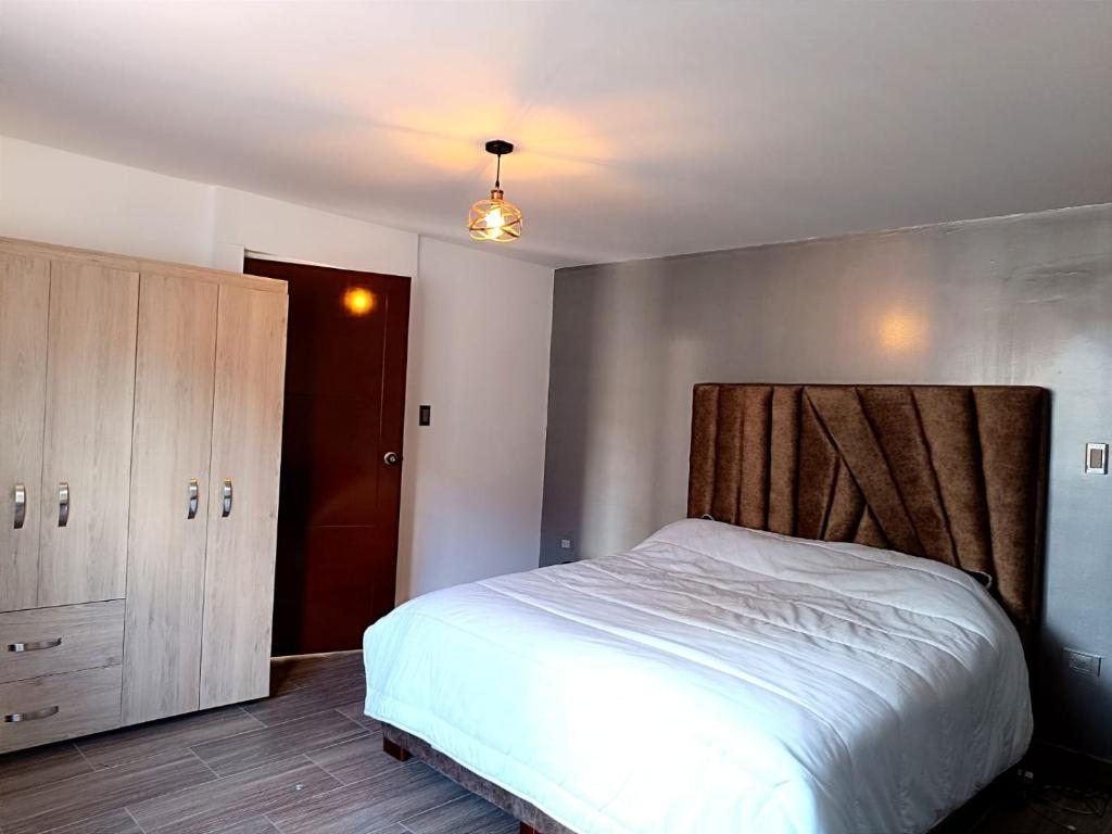 a bedroom with a white bed and a wooden headboard at LA PAZ! Espacios verdes y zona BBQ in Sogamoso