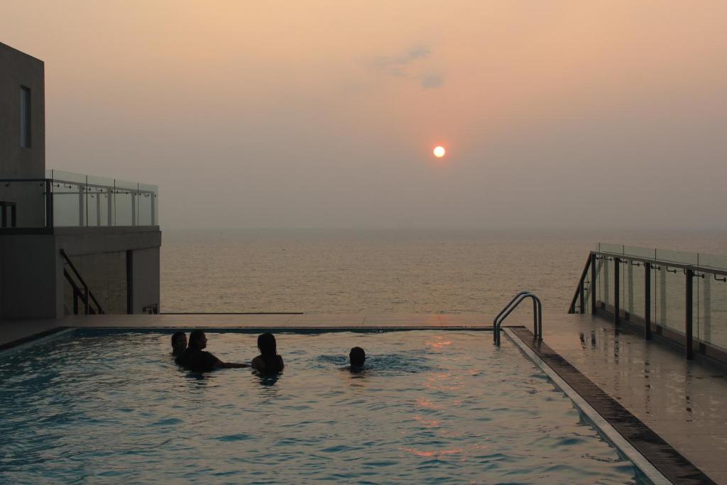 a group of people in a swimming pool overlooking the ocean at Luxury Ocean Condos by Travel Bee in Negombo