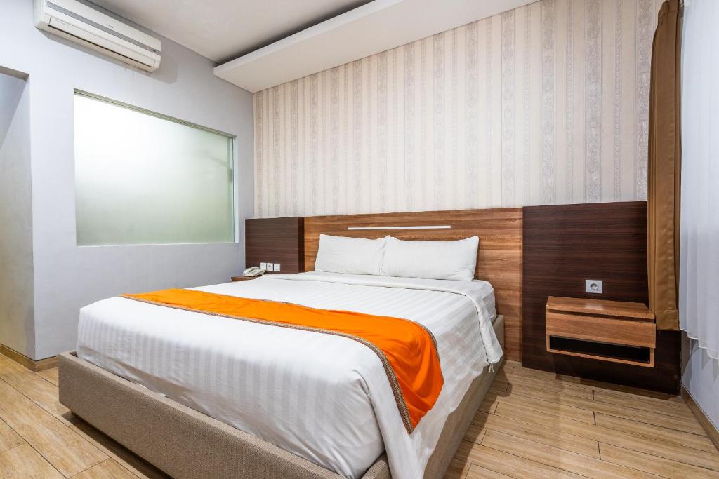 a bedroom with a large bed with an orange blanket at Casa Dasa Legian in Seminyak