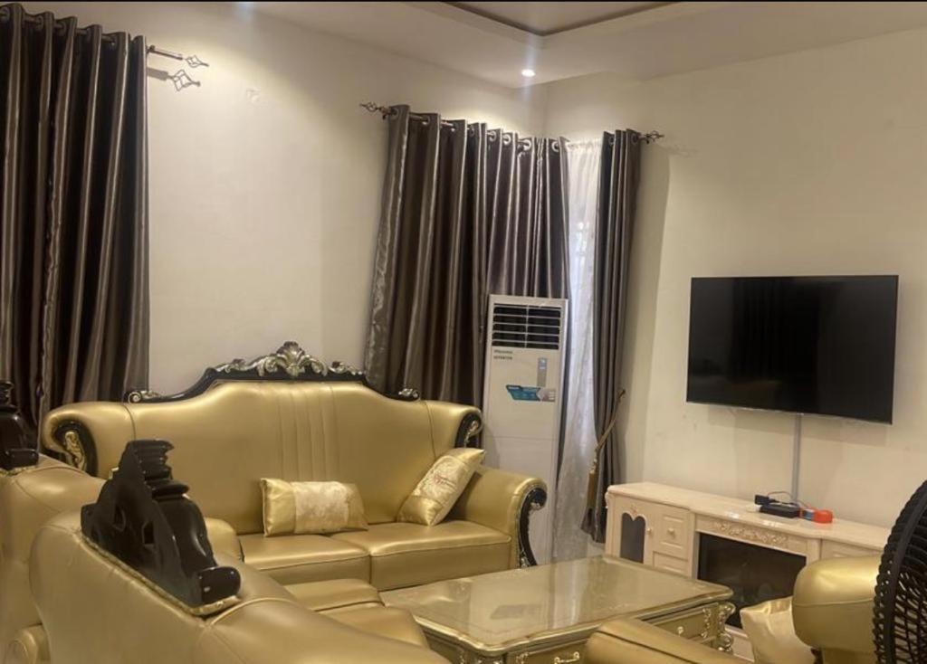 sala de estar con sofá y TV de pantalla plana en Luxurious Home - Isheri Magodo, en Agege