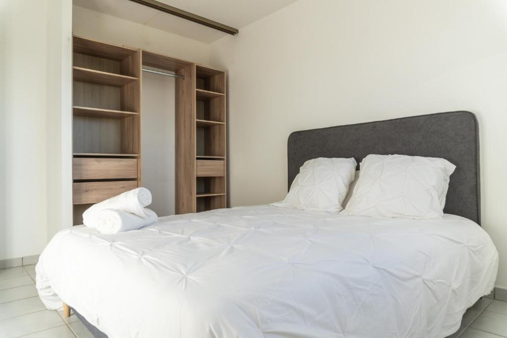 1 dormitorio con cama blanca y almohadas blancas en Location T2 Chic ducos proche de l'aéroport en Ducos