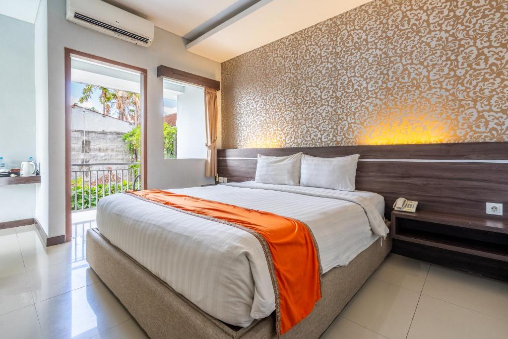 1 dormitorio con 1 cama grande con manta naranja en Casa Dasa Legian, en Seminyak