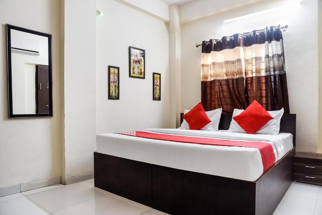 a bedroom with a large bed with red pillows at OYO Radhika Palace in Bhopal