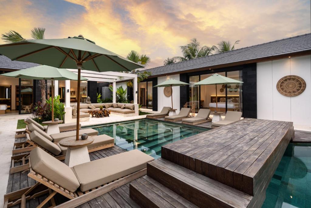 an outdoor pool with chairs and an umbrella at Villa Cocktail and Dreams by BaliSuperHost in Ubud