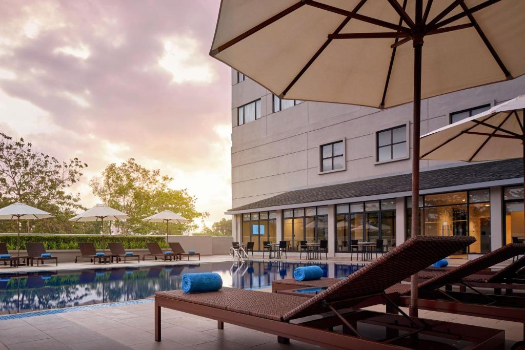 uma piscina com cadeiras e um guarda-sol ao lado de um edifício em AC Hotel by Marriott Kuantan em Kuantan