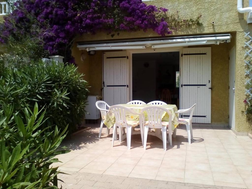 een tafel en stoelen op een patio met paarse bloemen bij Villa Le Barcarès, 3 pièces, 6 personnes - FR-1-782-22 in Le Barcarès