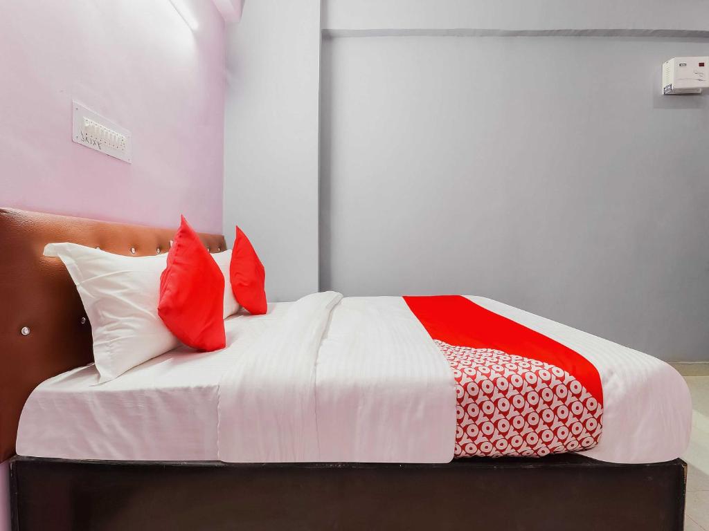 a bed with red and white pillows on it at OYO Flagship Kalawati Palace in Bhauli