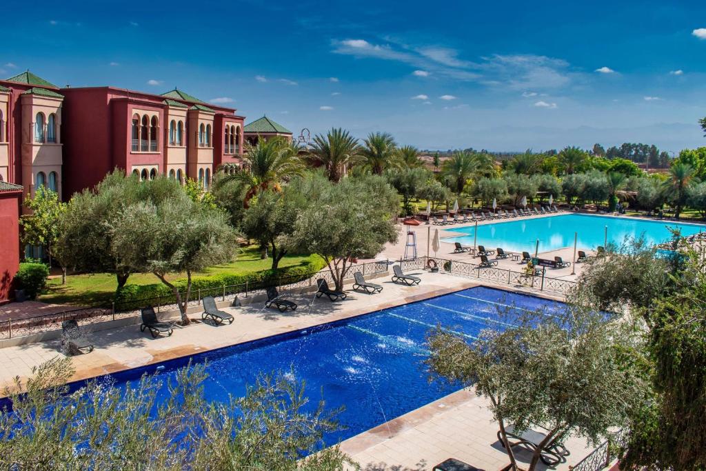 uma vista aérea de uma piscina de resort com cadeiras e árvores em Eden Andalou Aquapark & Spa em Marraquexe