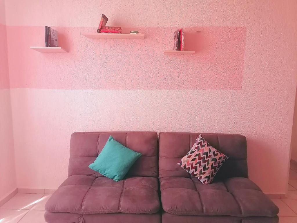 - un canapé brun avec 2 oreillers sur un mur rose dans l'établissement La casa gris, à Tulum