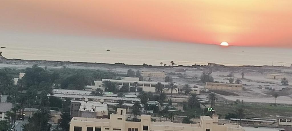 uma vista de uma cidade com o pôr-do-sol ao fundo em غرفه بشقه بأطلاله على البحر em ‘Izbat al Qaşr