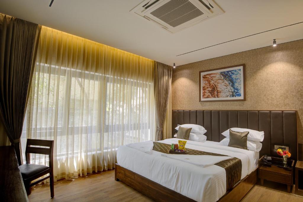 a bedroom with a bed and a chair and a window at Lance 21 - Ashok Nagar in Chennai