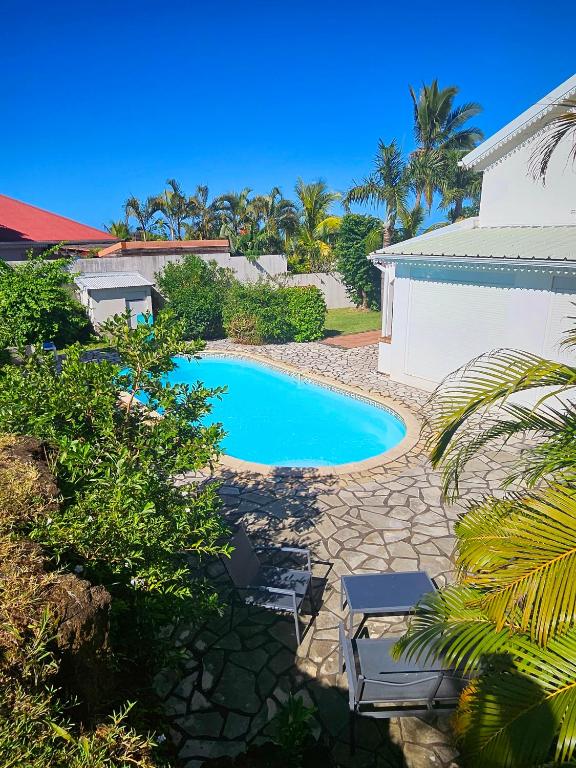 - une piscine avec 2 chaises à côté d'un bâtiment dans l'établissement Kaz Ô Flambloyant avec piscine privative, proche Grand'Anse, à Petite Île