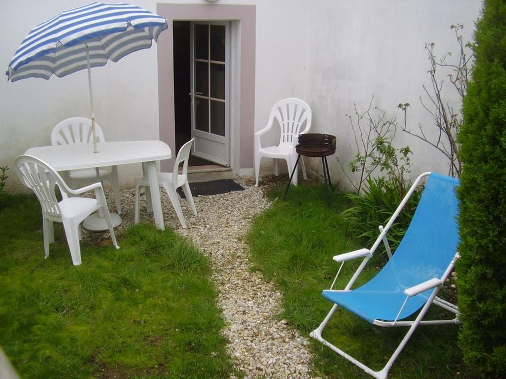 un patio avec une table, des chaises et un parasol dans l'établissement Charmante maison près sentier côtier, plage à 500m, Wi-Fi, animaux OK, terrasse, 2 pers - FR-1-418-252, à Locmaria