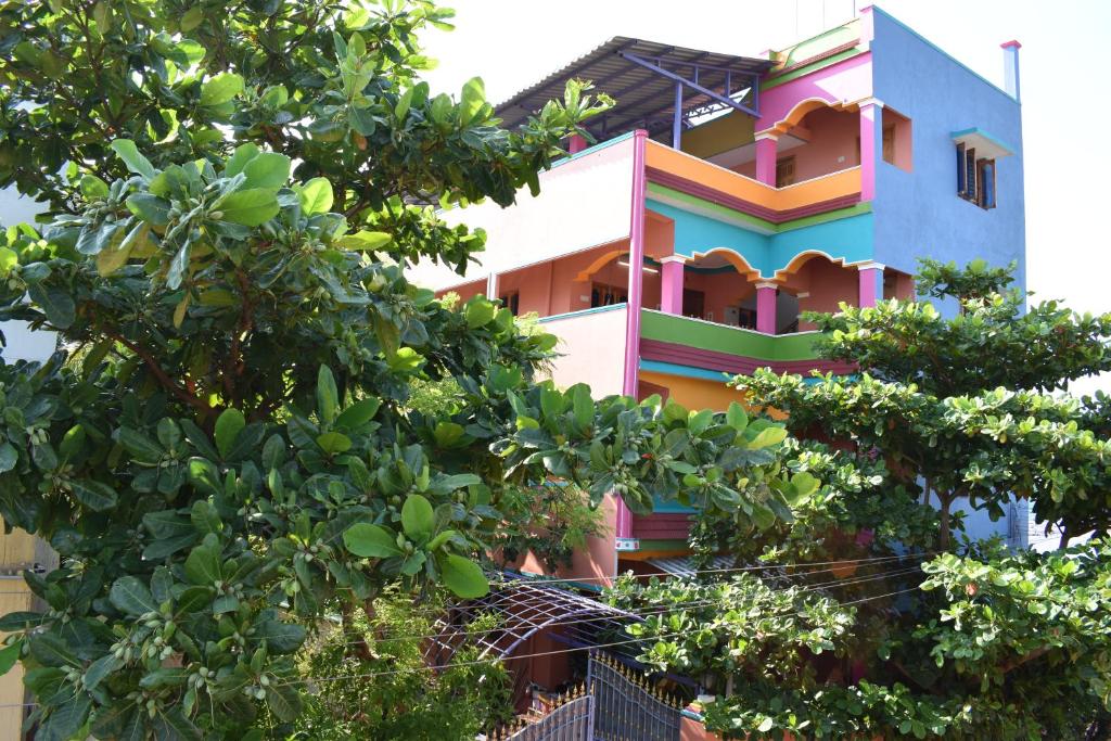 kolorowy budynek z drzewami przed nim w obiekcie Rainbow Guest House w mieście Tiruvannamalai