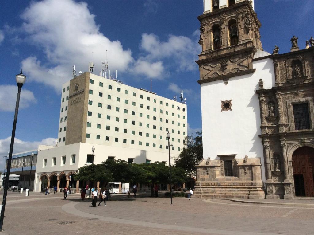 a large white building with a clock tower next to a building at Hotel San Francisco Irapuato Business Class in Irapuato