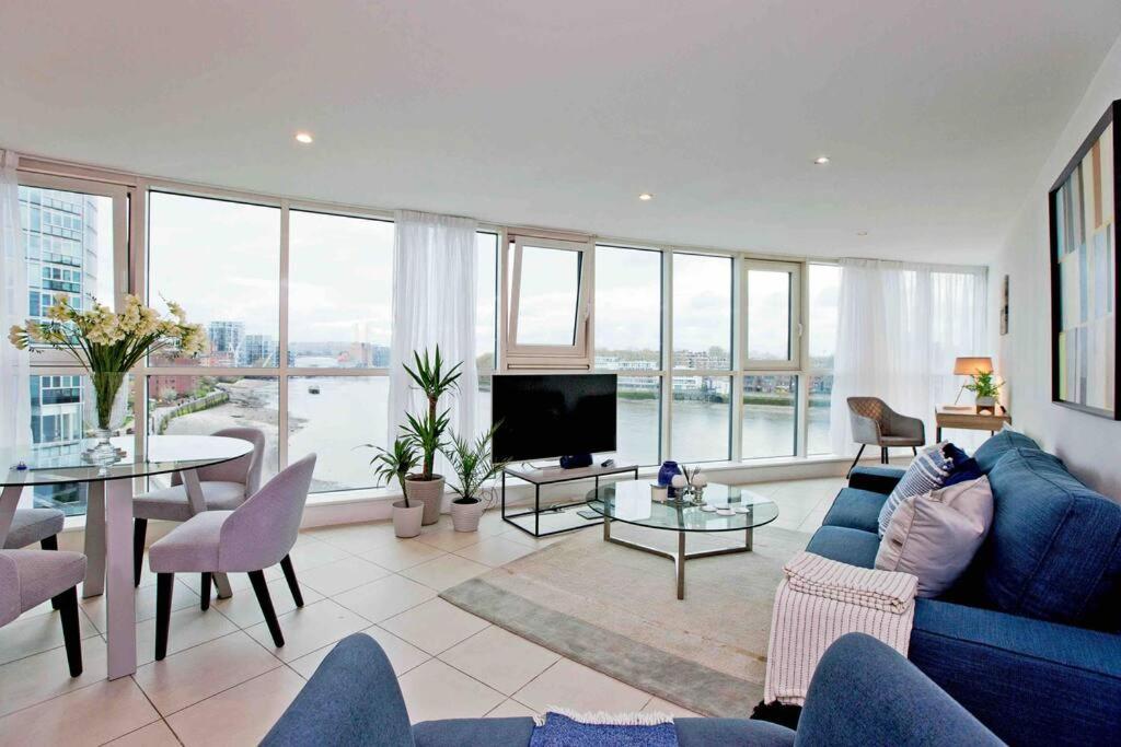 ein Wohnzimmer mit einem blauen Sofa und einem TV in der Unterkunft Lovely 2BD flat with River view in London