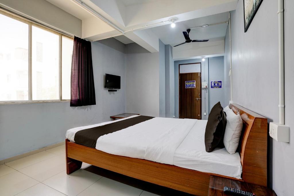 ein Schlafzimmer mit einem Bett und einem TV in der Unterkunft OYO Hotel Sama Residency in Vadodara