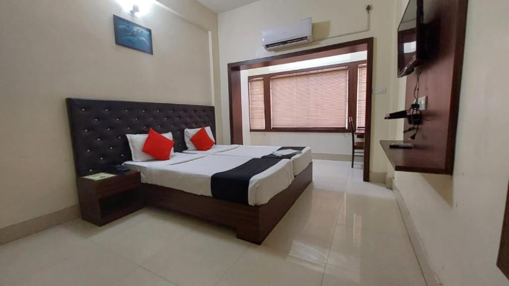 a bedroom with a bed with two red pillows at Hotel Tripletree Bhubaneswar in Bhubaneshwar