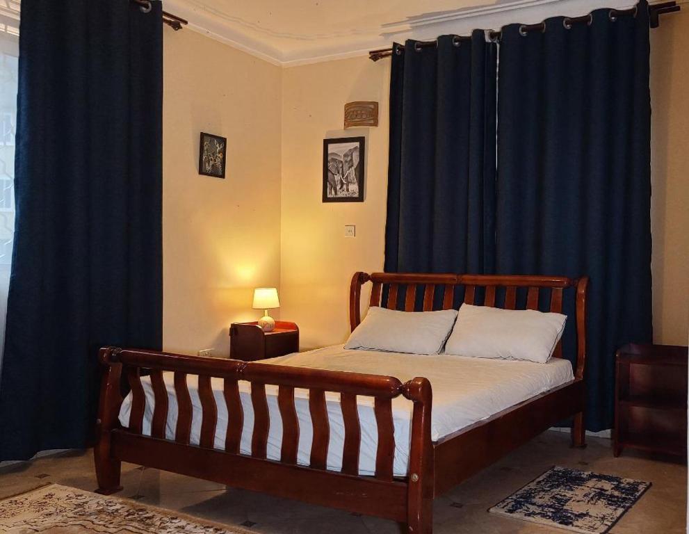 坎帕拉的住宿－HIS&HERS MOTEL by MATHIAS，一间卧室配有一张蓝色窗帘的床