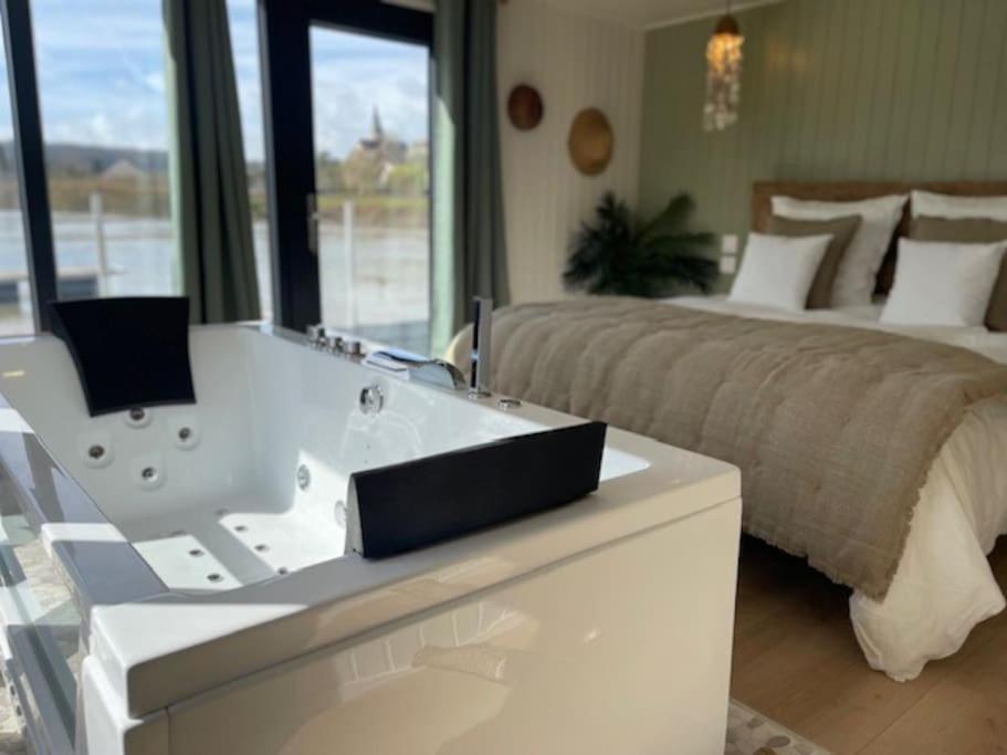 ein Schlafzimmer mit einem großen Bett und einer Badewanne in der Unterkunft Gîte Seine & Nature Le Capitaine in Bennecourt