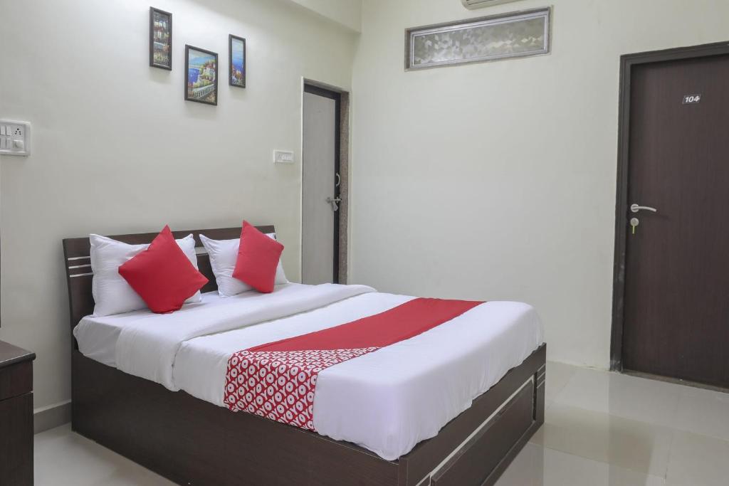 スーラトにあるCollection O Shyam Vatika Banquet And Roomsのベッドルーム1室(大型ベッド1台、赤い枕付)