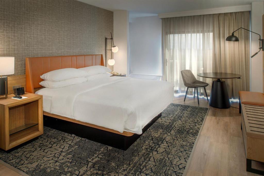 a bedroom with a large bed and a table at Sheraton Westport Plaza in Maryland Heights