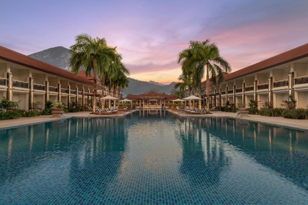 a large swimming pool with palm trees and a hotel at Four Points by Sheraton Palawan Puerto Princesa in Sabang