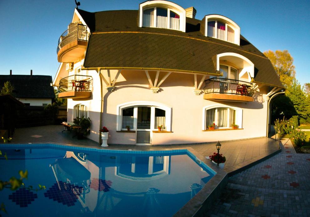 a house with a swimming pool in front of it at Muschel Panzió in Keszthely