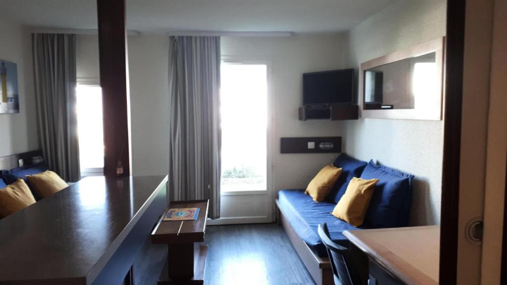 un salon avec un canapé bleu et une table dans l'établissement Résidence Port du Crouesty - maeva Home - Appartement 2 pièces 5 personnes - Confort MAE-9634, à Arzon