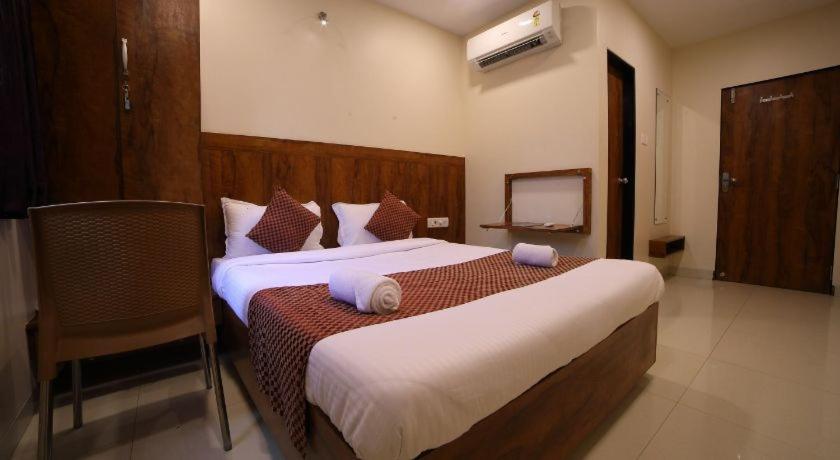 a hotel room with two beds and a chair at New Prakash Intl Airport in Mumbai