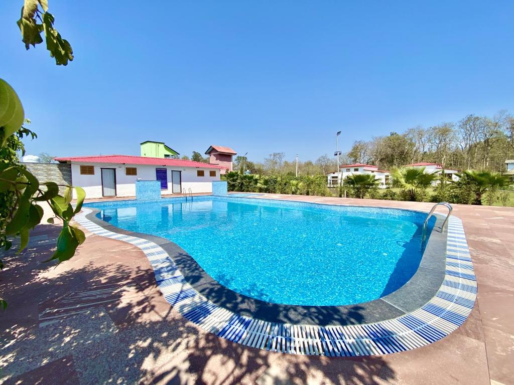 a swimming pool in front of a house at Hotel Corbett Bunglow By Food Bunglow in Rāmnagar