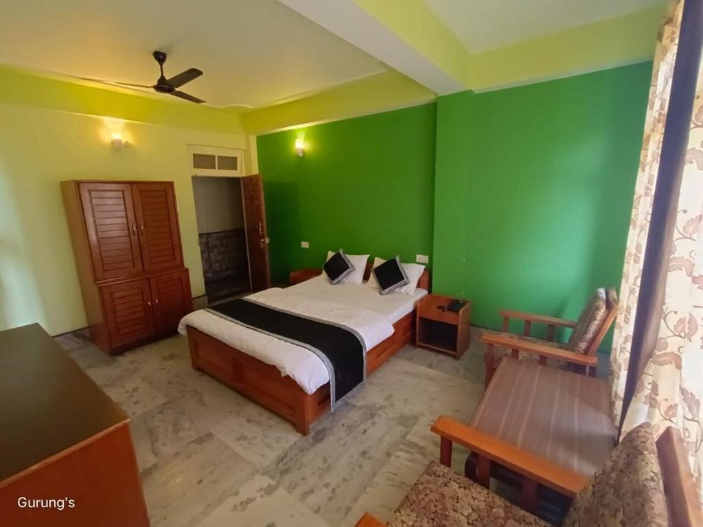 - une chambre avec un lit et un mur vert dans l'établissement Ecotel kalimpong, à Kalimpong