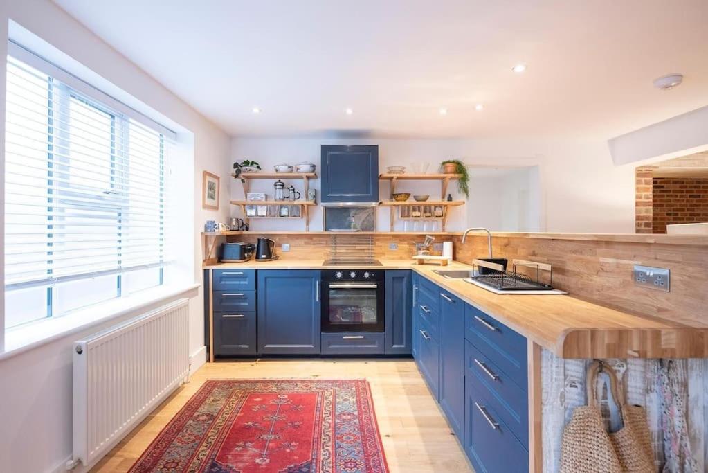 a kitchen with blue cabinets and a large window at Old Printing Press, Leiston in Leiston