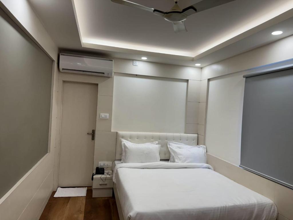 1 dormitorio con cama blanca y techo en Hotel Taj Akash en Deoghar