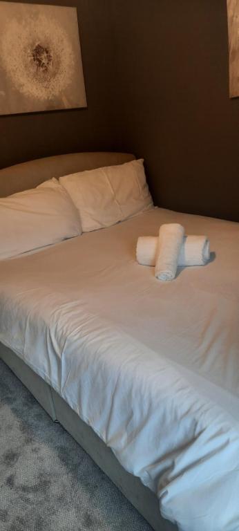 Boutique Guest House في غالواي: سرير عليه شراشف بيضاء وفوطين