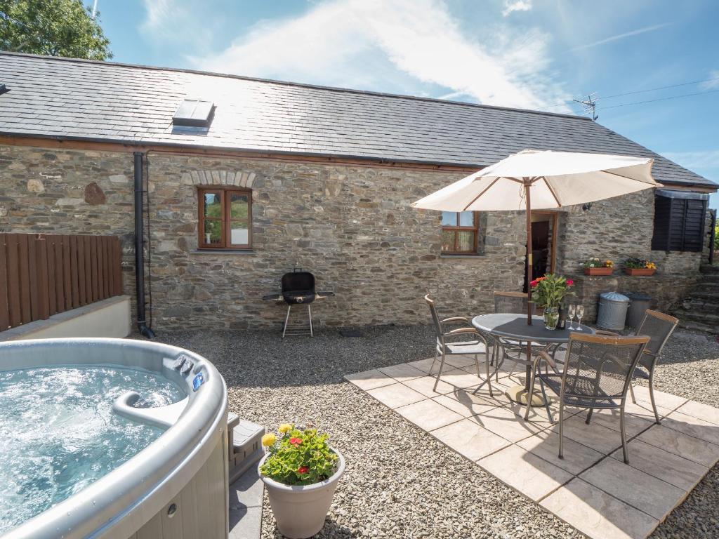 un patio con bañera de hidromasaje, mesa y sillas en Eirlys Llanrhystud, en Llanrhystyd