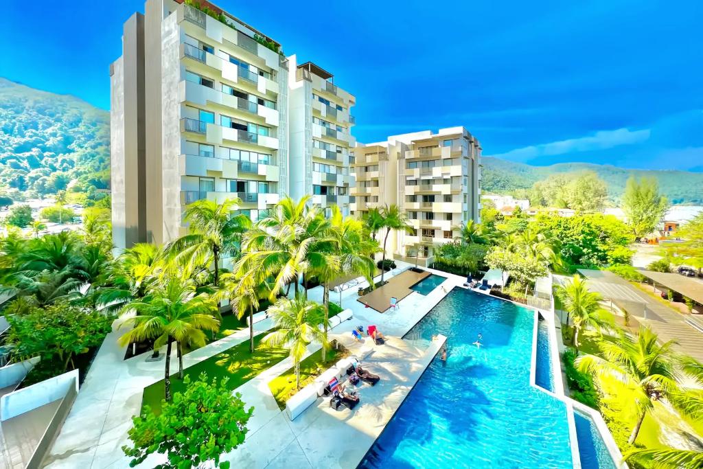 峇都丁宜的住宿－By The Sea Penang，享有棕榈树和建筑的游泳池的顶部景致