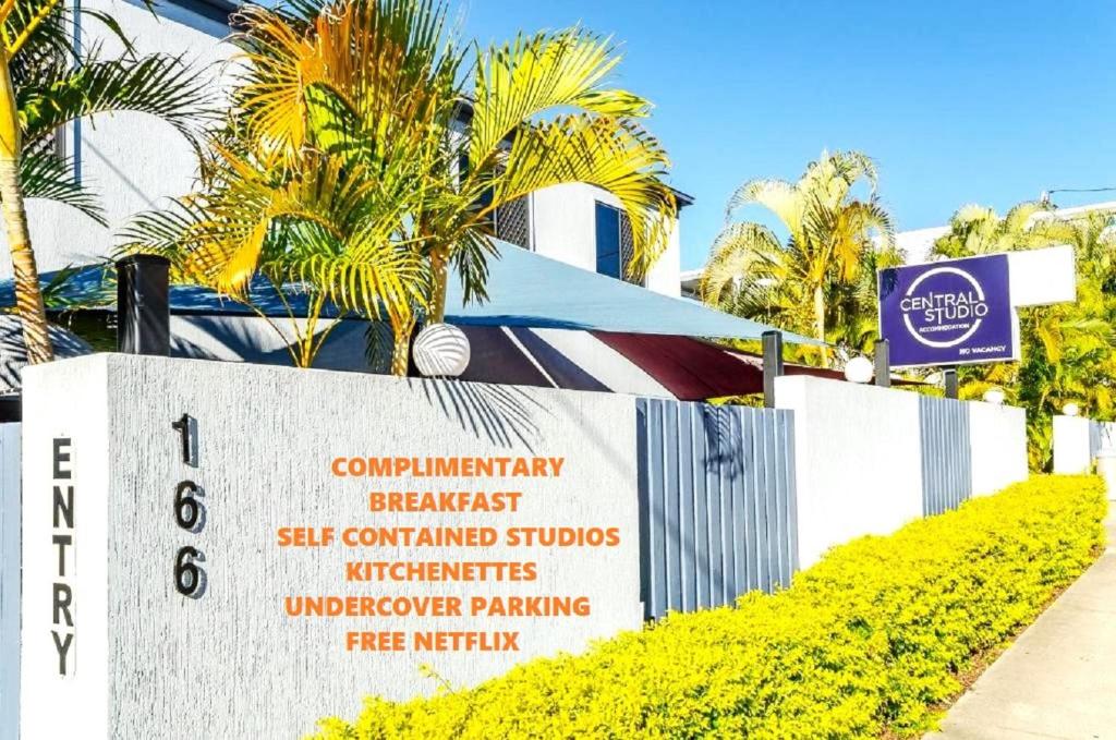 a sign in front of a building with palm trees at Central Studio Accommodation in Gladstone