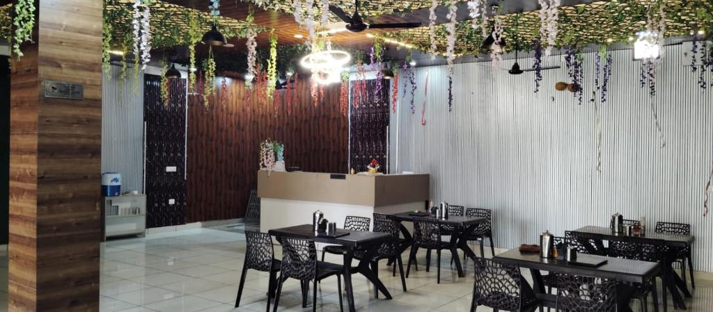 un restaurante con mesas negras, sillas y luces en Aroma Hotel & Restaurant, en Dādri