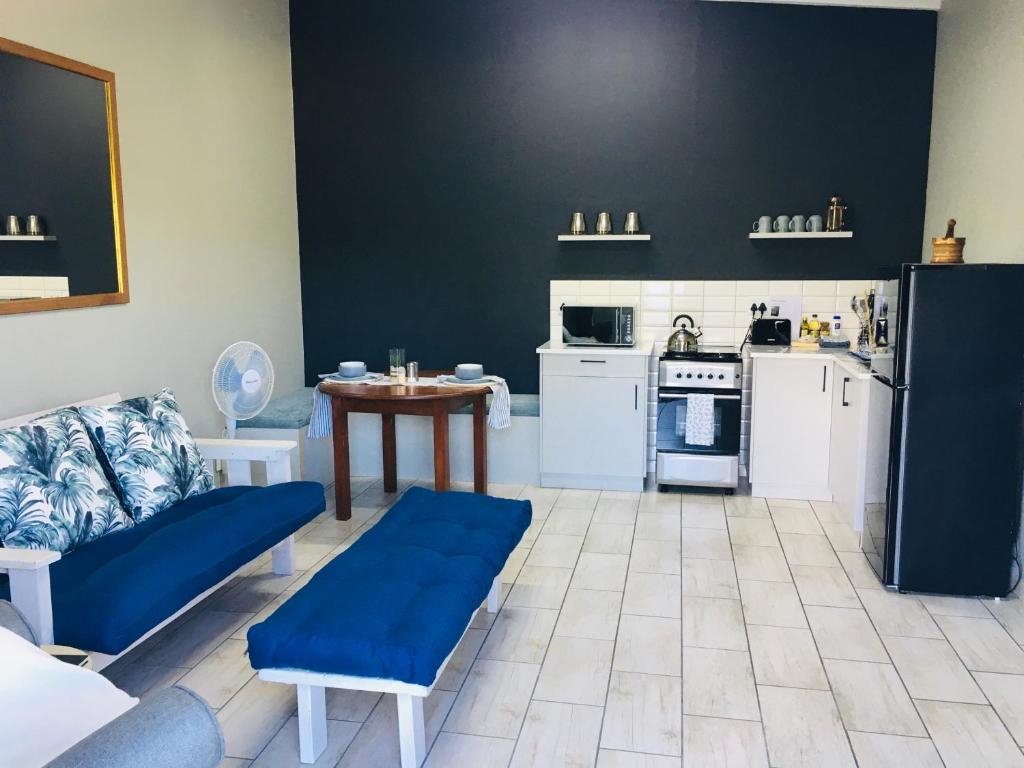 a living room with a blue couch and a kitchen at Happy Daze (Self catering) in Swellendam