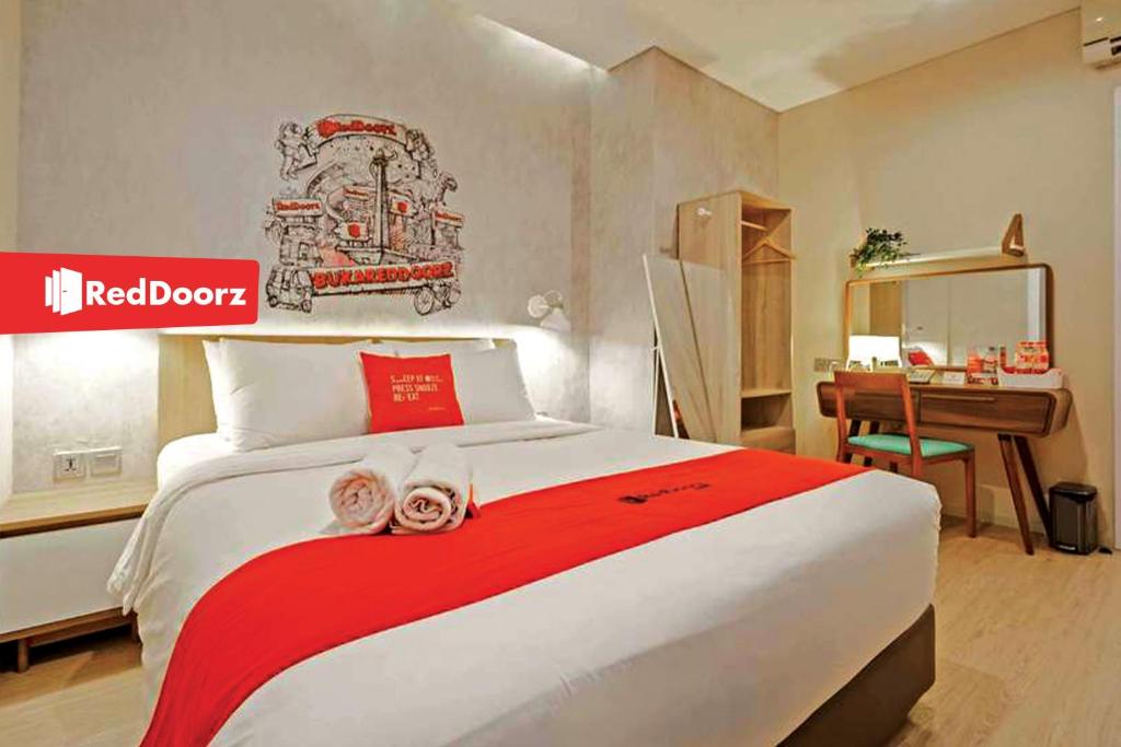 1 dormitorio con 1 cama grande, escritorio y frontera roja en Arwana Inn Lampung RedPartner en Bandar Lampung