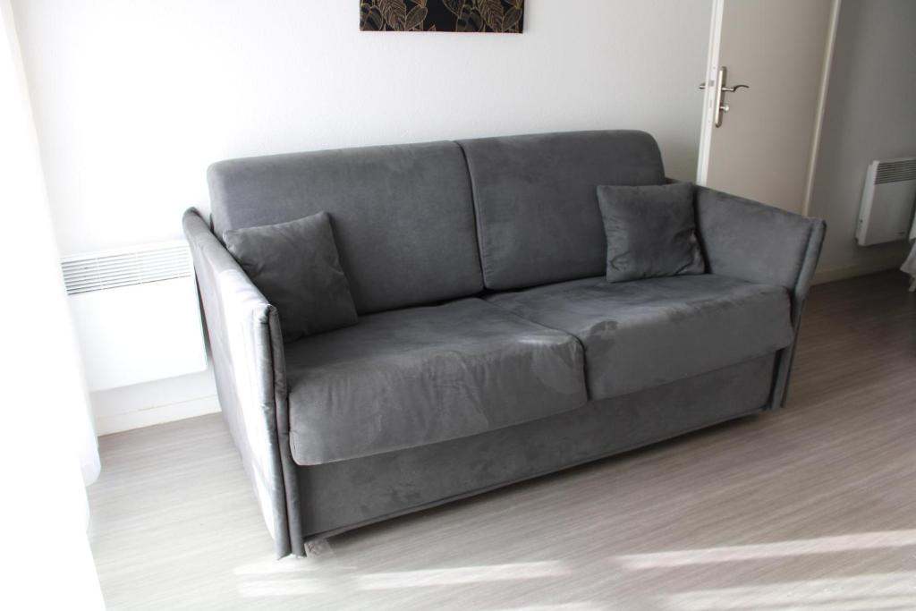 a gray couch in a living room at City Lodge Appart Hôtel Niort in Niort