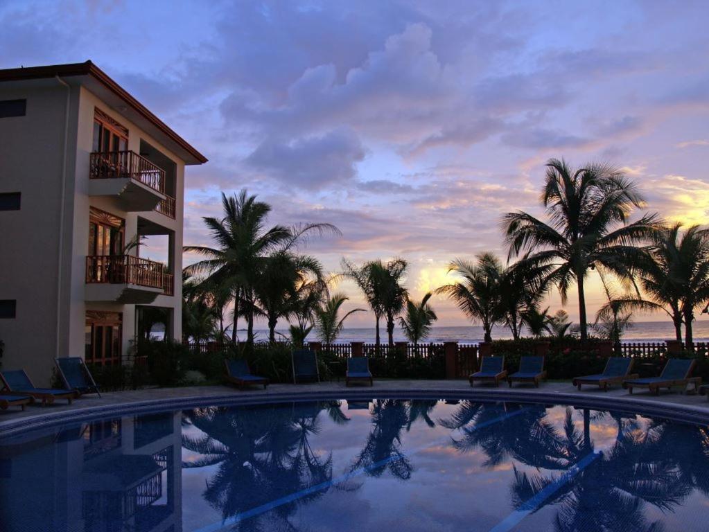una piscina con palmeras y un edificio en Bahia Azul 3A, en Jacó