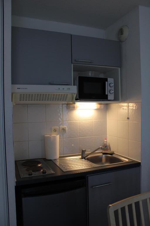 a kitchen with a sink and a microwave at City Lodge Appart Hôtel Niort in Niort