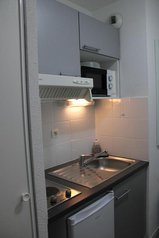 a small kitchen with a sink and a microwave at City Lodge Appart Hôtel Niort in Niort