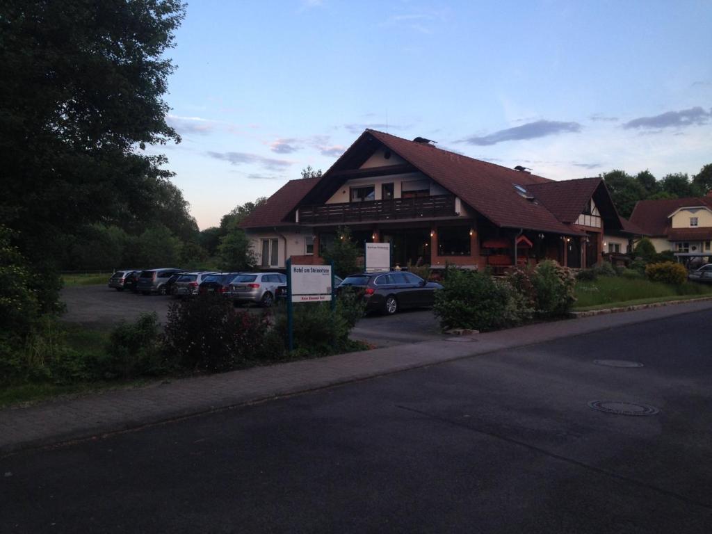 a building with cars parked in a parking lot at Hotel am Steinertsee - Kassel-Ost in Kaufungen