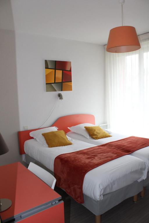 a hotel room with two beds and a table at City Lodge Appart Hôtel Niort in Niort