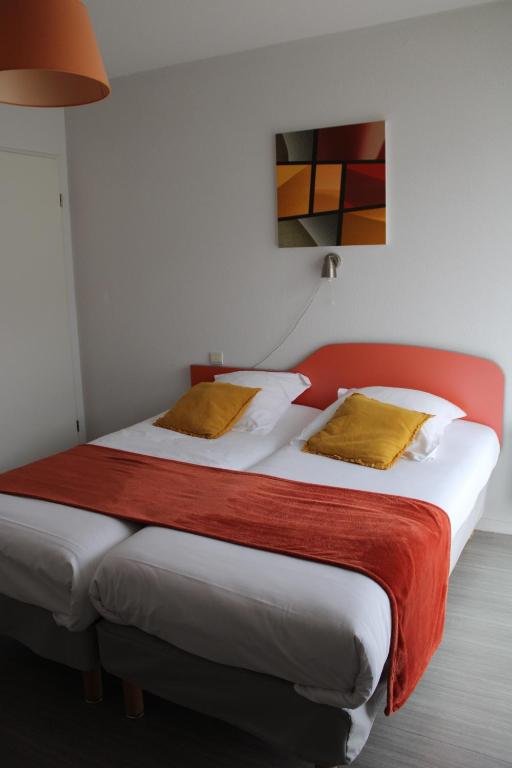 a bedroom with a large bed with a red headboard at City Lodge Appart Hôtel Niort in Niort