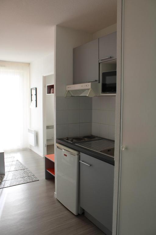 a kitchen with white cabinets and a stove top oven at City Lodge Appart Hôtel Niort in Niort