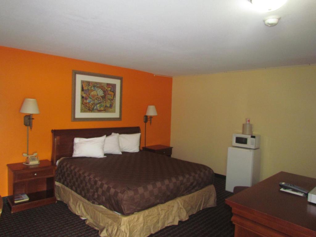 a hotel room with a bed and orange walls at Red Carpet Inn - Augusta in Augusta